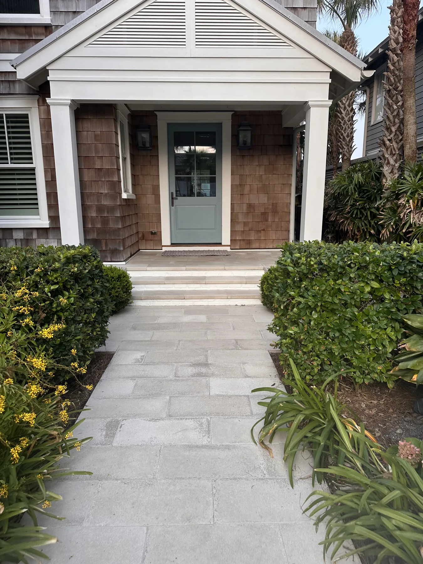 The front entry, clean stone pavers between greenery